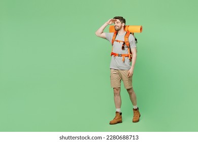 Full body young traveler white man carry backpack stuff mat walk look far away distance isolated on plain green background. Tourist leads active healthy lifestyle. Hiking trek rest travel trip concept - Powered by Shutterstock