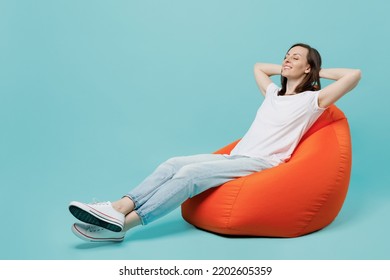 Full Body Young Woman 20s She Wear White T-shirt Sit In Bag Chair Hold Hands Behind Neck Sleeping Take Nap Isolated On Plain Pastel Light Blue Cyan Background Studio Portrait. People Lifestyle Concept