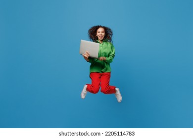 Full Body Young IT Woman Of African American Ethnicity 20s She Wear Green Shirt Jump High Hold Use Work On Laptop Pc Computer Isolated On Plain Blue Background Studio Portrait People Lifestyle Concept