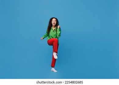 Full body young woman of African American ethnicity 20s she wear green shirt doing winner gesture celebrate clenching fists say yes isolated on plain blue background studio. People lifestyle concept - Shutterstock ID 2254802685