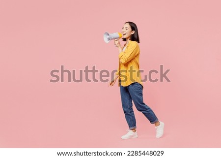 Full body young woman of Asian ethnicity wear yellow shirt white t-shirt hold megaphone scream announces discounts sale Hurry up going isolated on plain pastel light pink background studio portrait