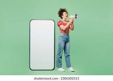 Full body young woman she wearing casual clothes red blouse big huge blank screen mobile cell phone smartphone with area screaming in megaphone isolated on plain pastel light green color background - Powered by Shutterstock