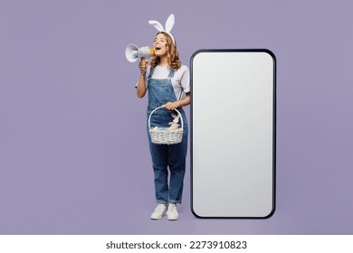 Full body young woman wear casual clothes bunny rabbit ears near big huge blank screen mobile cell phone with area scream shout in megaphone isolated on plain purple background. Happy Easter concept - Powered by Shutterstock