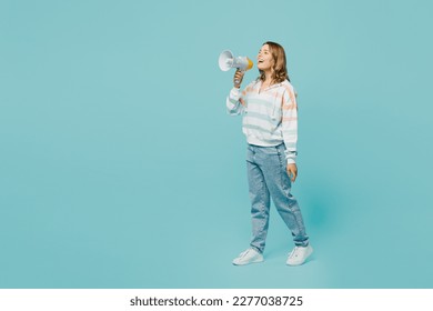 Full body young woman wear striped hoody hold in hand megaphone scream announces discounts sale Hurry up alk, go isolated on plain pastel light blue cyan background studio portrait. Lifestyle concept