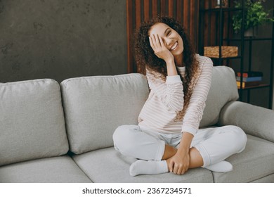 Full body young woman wear casual clothes sits on grey sofa couch look cmaera cover face with hand palm stay at home hotel flat rest relax spend free spare time in living room indoor. Lounge concept - Shutterstock ID 2367234571