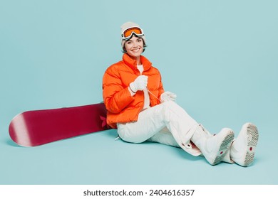 Full body young woman wear warm padded windbreaker jacket hat ski goggles lace up boots sit with snowboard mask travel rest spend weekend winter season in mountains isolated on plain blue background - Powered by Shutterstock