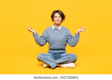 Full body young woman wears grey knitted sweater casual clothes sits hold spreading hands in yoga om aum gesture relax meditate try to calm down isolated on plain yellow background. Lifestyle concept - Powered by Shutterstock