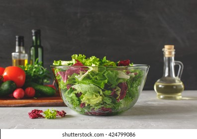 Full bowl of fresh green salad close up on a light table against a dark background on a rustic kitchen. Concept helpful and simple food - Powered by Shutterstock