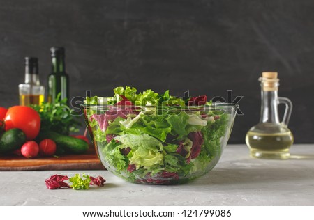 Full bowl of fresh green salad close up on a light table against a dark background on a rustic kitchen. Concept helpful and simple food