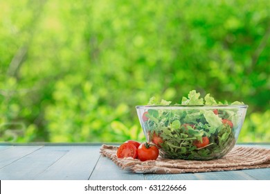 Full bowl of fresh salad on a wooden table  against the background blur green leaves bokeh