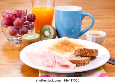 Full breakfast consisting of toast, jam, bread, cereal, ham, orange juice, grapes and kiwi - Powered by Shutterstock