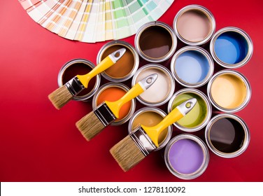 Full Buckets Of Rainbow Colored Oil Paint On Red Background