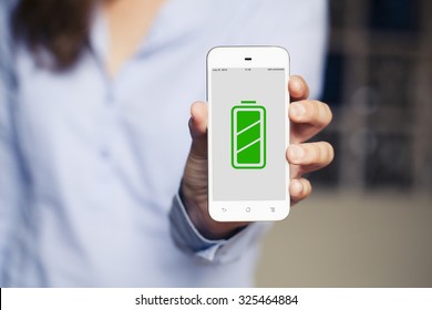 Full Charged Battery Green Icon In A Mobile Phone Screen. Woman Holding It In The Hand.