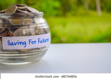 Full Of Coins In Glass Bowl On White Table With Nature Background,concept Saving For The Future.For Children Education,new House,the First Car,retirement And Emergency. Include National Savings Day.