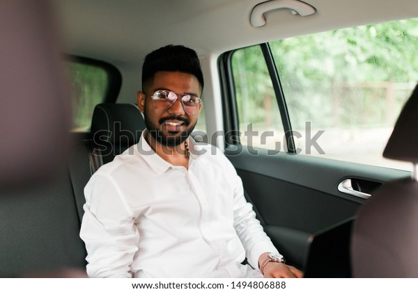 Full concentration\
at work. Confident young man in full suit working using laptop\
while sitting in the car