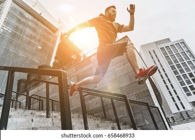 Full of energy. Full length of handsome young man in sport clothing jumping while exercising outside