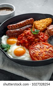 Full English Breakfast With Bacon, Sausage, Fried Egg, Baked Beans, Hash Browns And Mushrooms In Rustic Skillet, Pan. Cup Coffee.