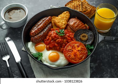 Full English Breakfast With Bacon, Sausage, Fried Egg, Baked Beans, Hash Browns And Mushrooms In Rustic Skillet, Pan. Cup Coffe, Orange Juice