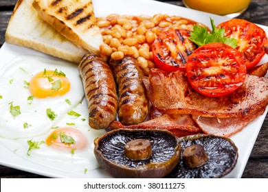 Full English breakfast with bacon, sausage, fried egg, baked beans and mushrooms.