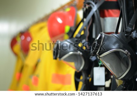 Full face mask with self contained breathing apparatus (SCBA) including fire suit and personal protective equipment (PPE) on the wall to stand by for firefighters at chemical plants, power plants.