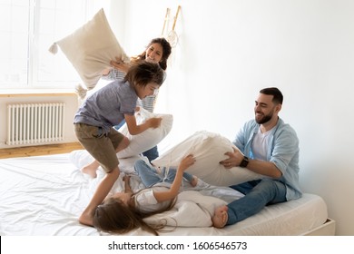 Full Family With Little Daughter Son Fool Around Playing With Cushions Holding Pillows Spend Funny Time On Bed In Bedroom, Laughing Having Fun Enjoy Fight And Active Game At Home Feels Happy Concept