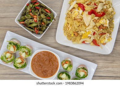 Full Feast Of Spicy Thai Food On The Wooden Table With The Featured Dish Being The Fresh Shriimp Rolls.