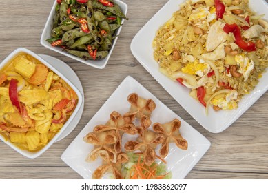 Full Feast Of Spicy Thai Food On The Wooden Table With The Featured Dish Being The Star Shaped Wontons.