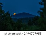 The full flower moon -  07, 2024. The rising moon over the mountain peaks , a cloudless night allows observation of the astronomical phenomenon. 