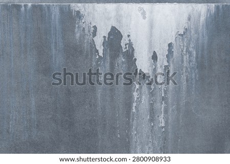 Full frame abstract background of a weathered grey cement tile panel with severe water damage and white salt stains. Rough industrial concrete surface with mineral efflorescence deposits, moisture defects and chemical erosion.