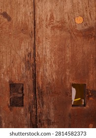 Full frame abstract texture of a rustic weathered red-brown wooden door with a rectangular mortise hole.