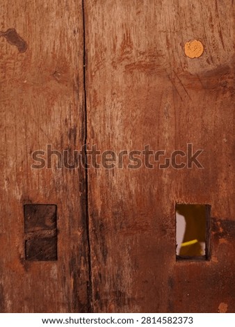 Full frame abstract texture of a rustic weathered red-brown wooden door with a rectangular mortise hole.