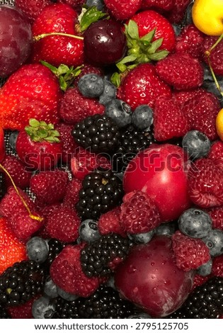 Full frame background of fresh mixed berries and fruits including strawberries, raspberries, and blueberries.