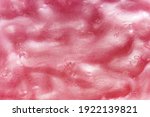 Full frame background of gooey pink slime, a kids toy produced with guar gum with an amorphous malleable squishy slimy texture in close up detail