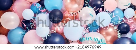 Full frame background of multicolored balloons of different sizes and bright serpentine stacked in light room during festive event celebration