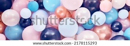 Full frame background of pile of various bright balloons of different colors and sizes stacked together in light decorated room during festive event celebration