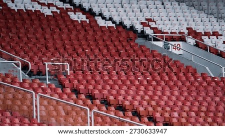 Full frame background of repeating white stadium seats with red numbered stickers at Gelora Bung Karno (GBK) Stadium.