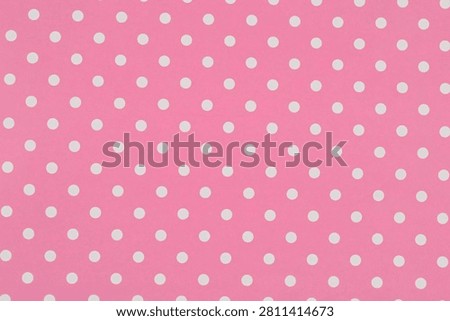 A full frame background texture shows a seamless and sweet pattern of small white polka dots evenly distributed across a pink paper surface.