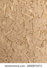 Full frame background texture of a traditional cob wall made from cracked dried mud and straw bricks.