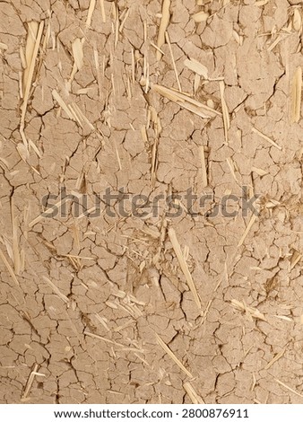 Full frame background texture of a traditional cob wall made from cracked dried mud and straw bricks.