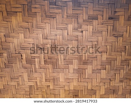 Full frame background texture of traditional woven bamboo matting showing intricate crisscross craftsmanship