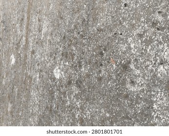 Full frame background texture of weathered rough concrete surface with grunge stains. A close-up view of a rustic unpainted concrete wall surface showing aged atmospheric grunge stains during daytime.