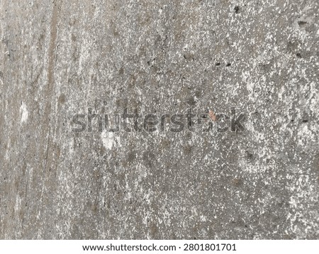 Full frame background texture of weathered rough concrete surface with grunge stains. A close-up view of a rustic unpainted concrete wall surface showing aged atmospheric grunge stains during daytime.
