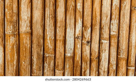 Full frame background of weathered vertical brown bamboo poles texture.