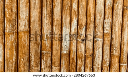 Full frame background of weathered vertical brown bamboo poles texture.