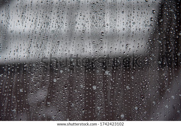 Full frame car glass covered with water\
drops as a backdrop. Copy space for text,\
design.