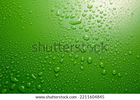 Full frame of clean green background covered with various drops of water flowing down in light room during rainy weather