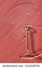 Full Frame Closeup Of A Red Barn With Wooden Siding And A Simple Metal Hook.