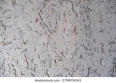 Full frame close-up of a textured, light-colored painted cork material showing deep crevices, rough patterns, and organic porous details.