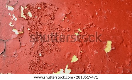Full frame closeup of a vibrant red painted concrete wall with rough bumpy texture and blistered surface for background design.