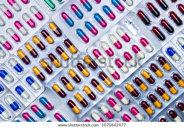 Full frame of colorful antimicrobial capsule\
pills. Quality control error in pharmaceutical manufacturing.\
Blister pack missing one capsule of antibiotic pill. Drug\
resistance. Defective\
concept.